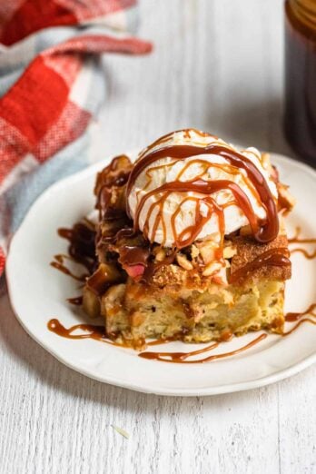 Plate of the apple bread pudding with ice cream on top and caramel sauce drizzle over
