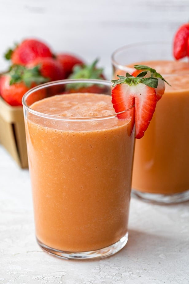 A strawberry mango smoothie garnished with a fresh strawberry