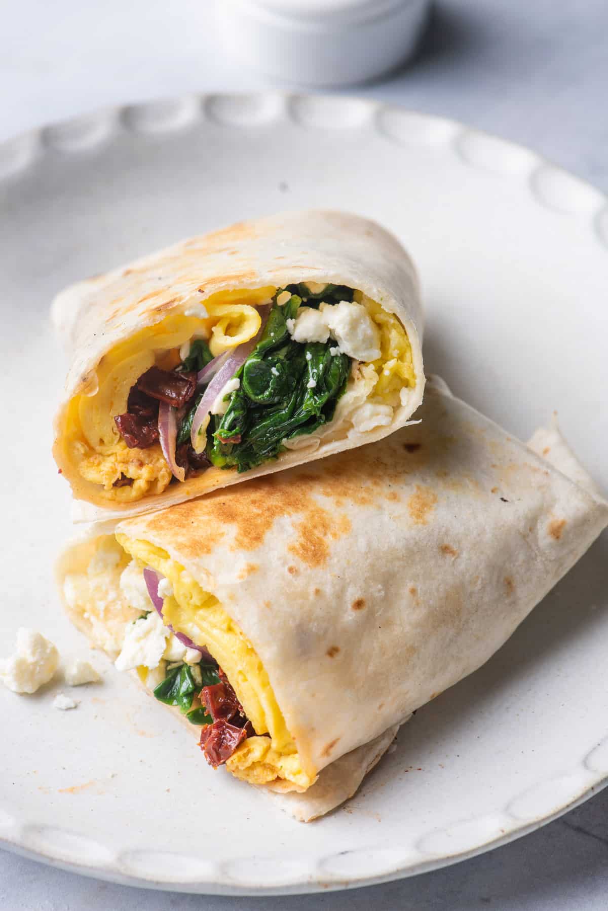 Mediterranean egg wrap cut in half on a white plate