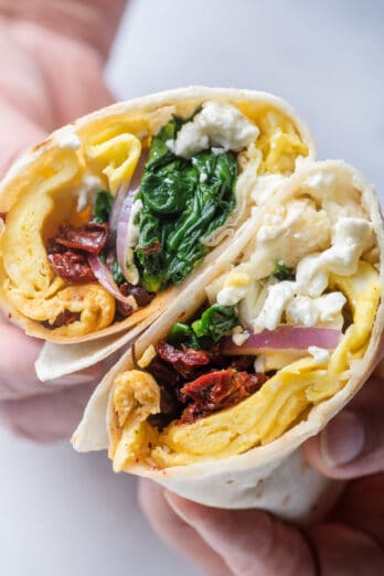 Handles holding two halves of mediterranean egg wrap to show what's inside the wrap