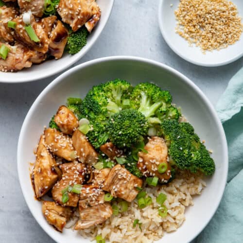 Chicken Teriyaki, Brown Rice and Broccoli in bowls with sesame seeds on the side
