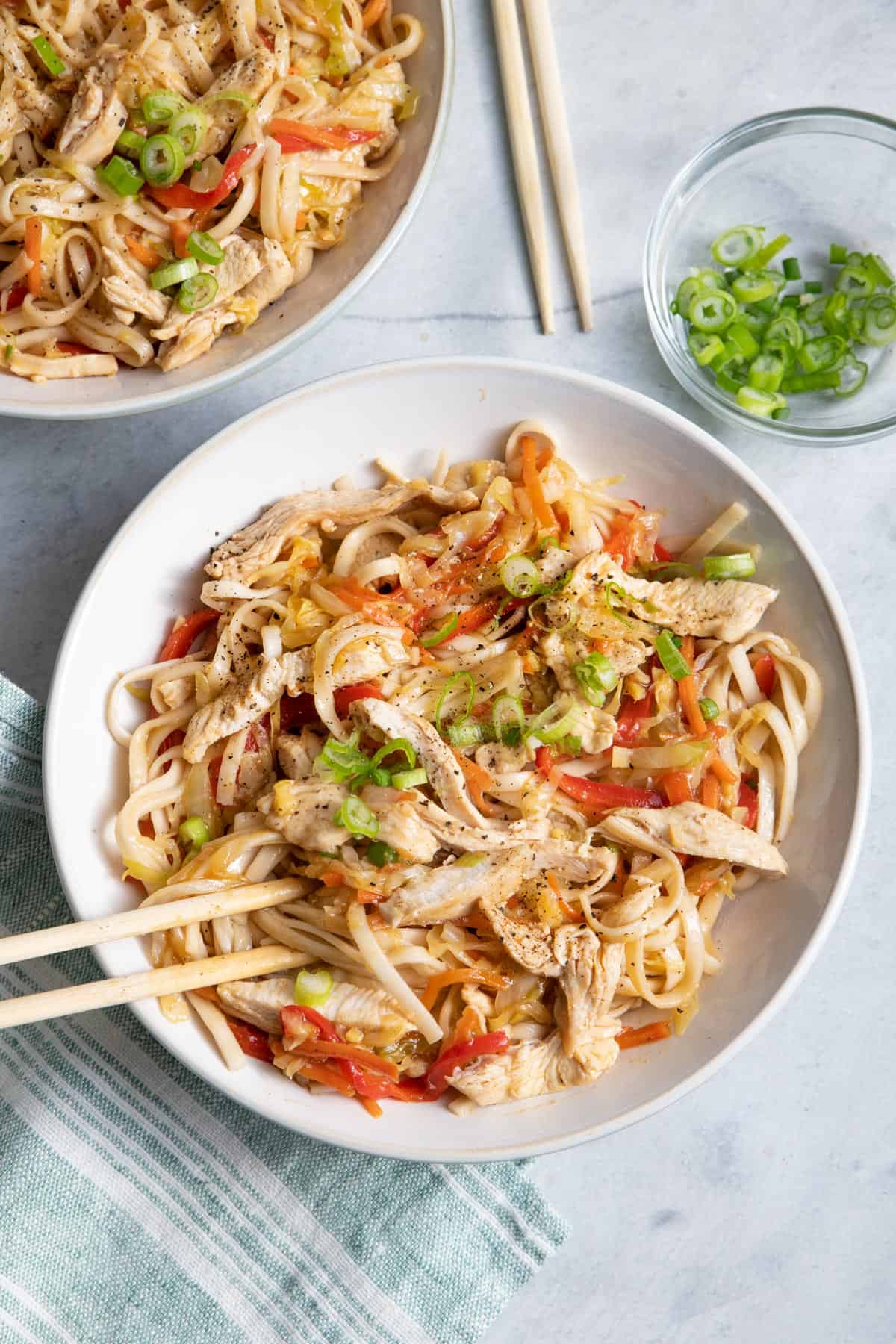Two bowls of Chinese inspired chicken lo mein with noodles and vegetables
