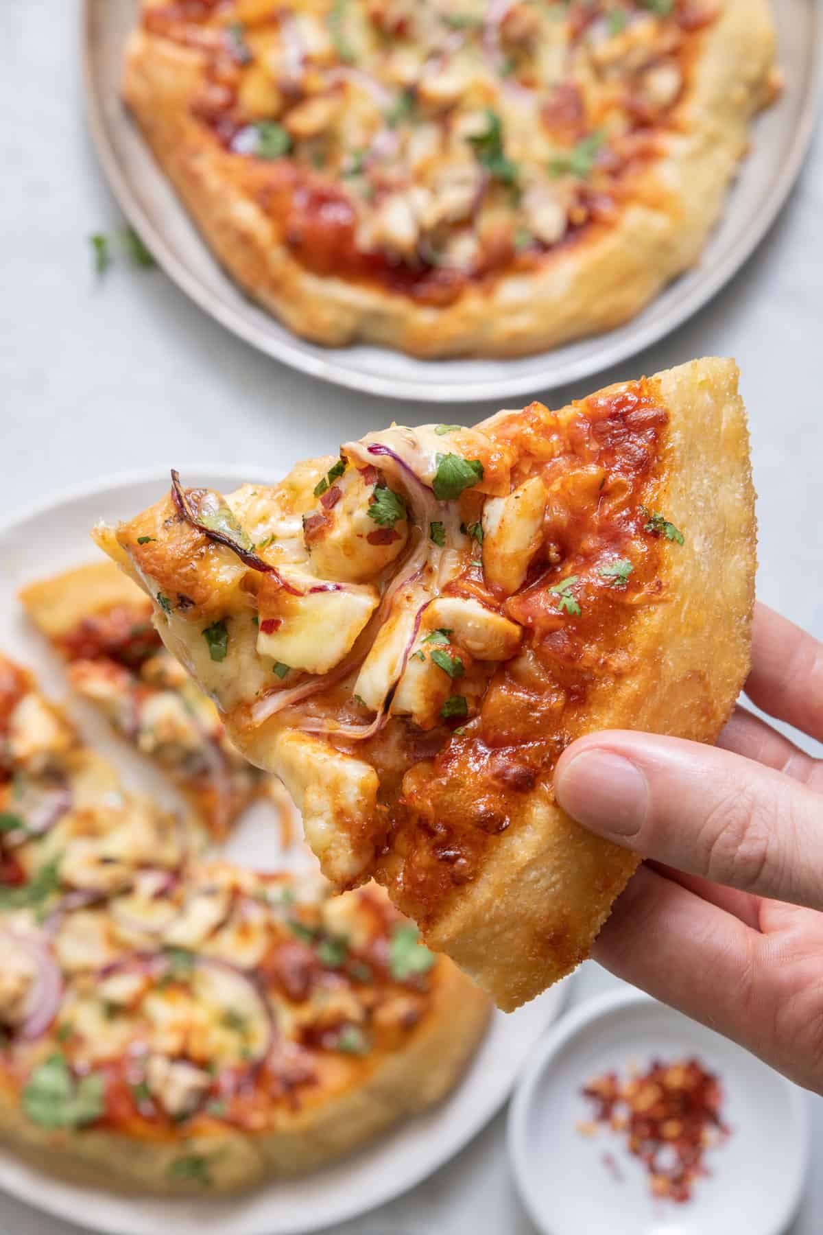 Pulling out one slice of pizza with two whole pizza in view under slice.