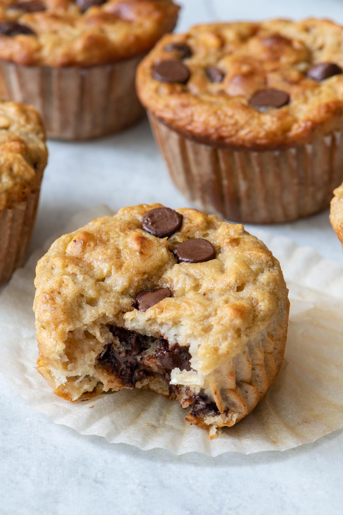 Bite taken out of muffin to show texture with other muffins around.