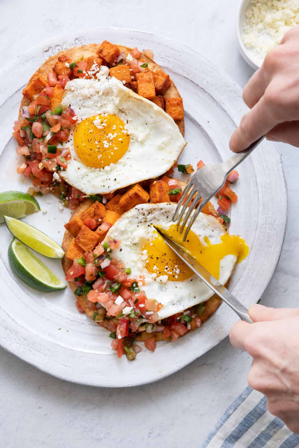 Knife and fork cutting into running egg over recipe