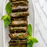 Final stuffed grape leaves lined up on a long plate