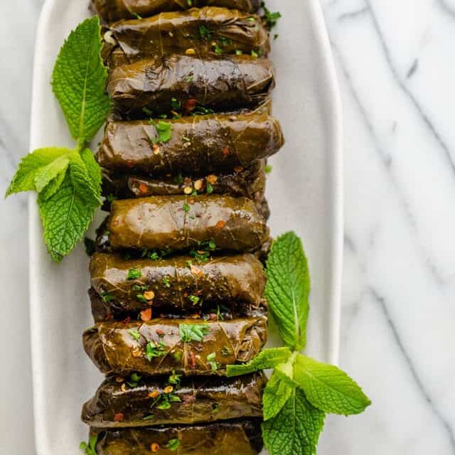 Final stuffed grape leaves lined up on a long plate