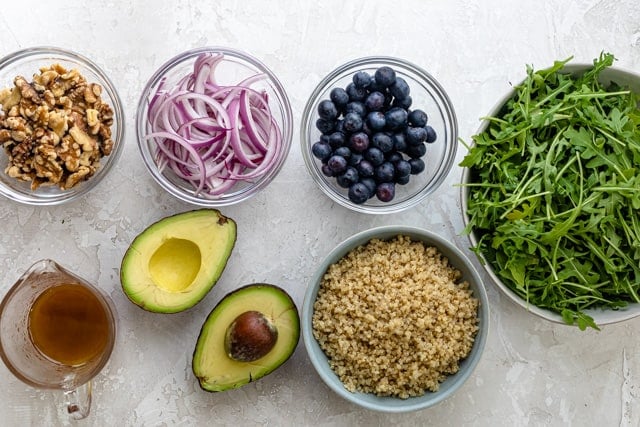 Ingredients to make the recipe: arugula, quinoa, blueberries, onions, walnuts, avocado and dressing