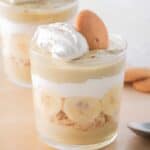 Two glasses filled with layered banana pudding parfaits.