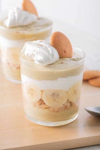 Two glasses filled with layered banana pudding parfaits.