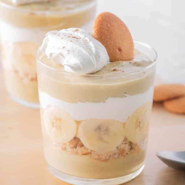 Two glasses filled with layered banana pudding parfaits.