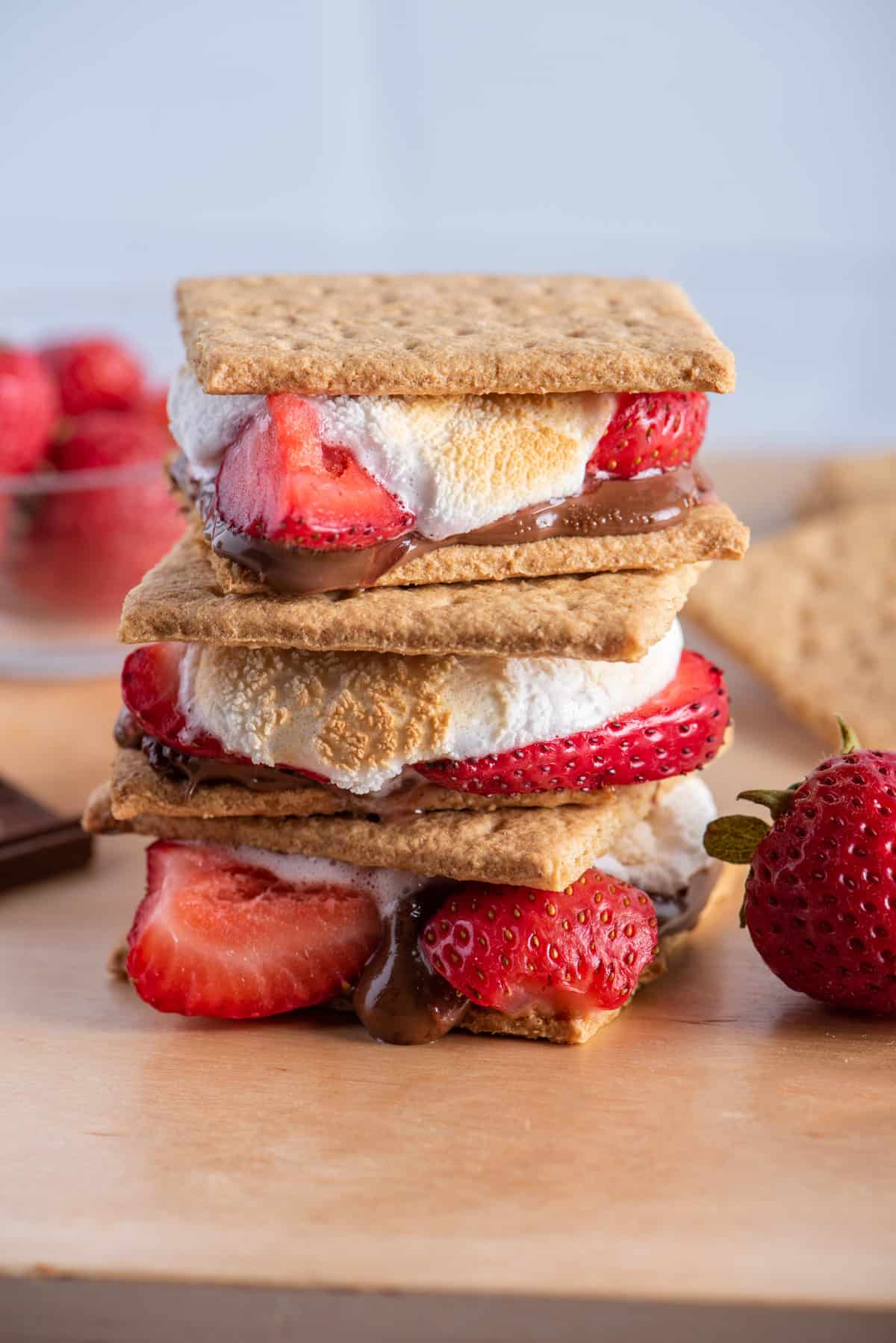 3 stacks of strawberry smores on a cutting board