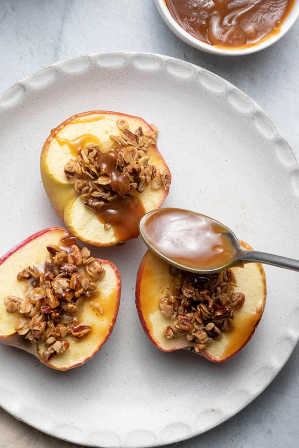 Spoon with caramel sauce going over the cinnamon bakedapples
