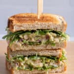 Stack of two halves of white bean avocado sandwich with toothpick holding them together
