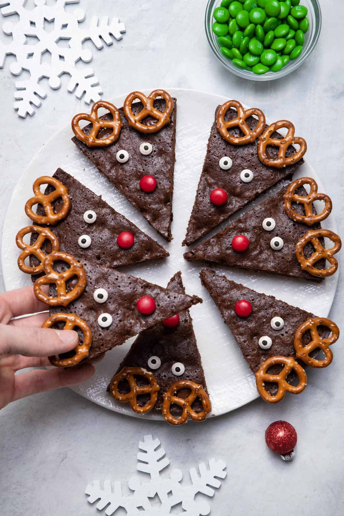 Hand grabbing one of the reindeer brownies from round white platter