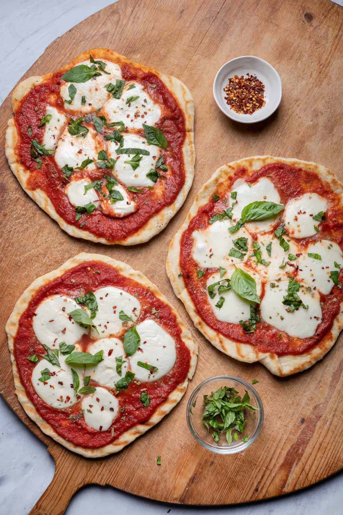 3 grilled pizzas on a large cutting board