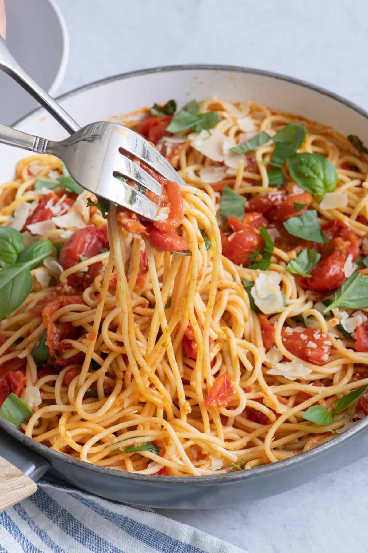 Pan of pasta and fork and spoon scooping a serving.