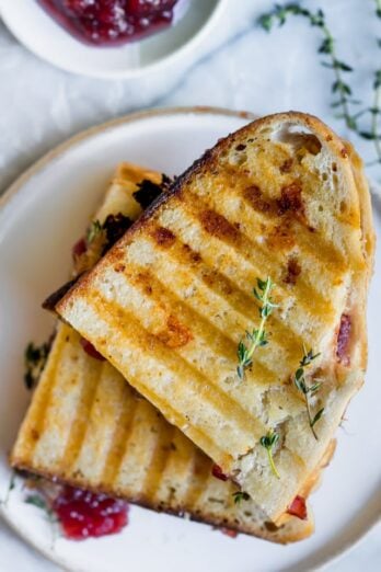Final outcome of the turkey panini showing two halves of the sandwich stacked on top of each other with a aside of cranberry sauce