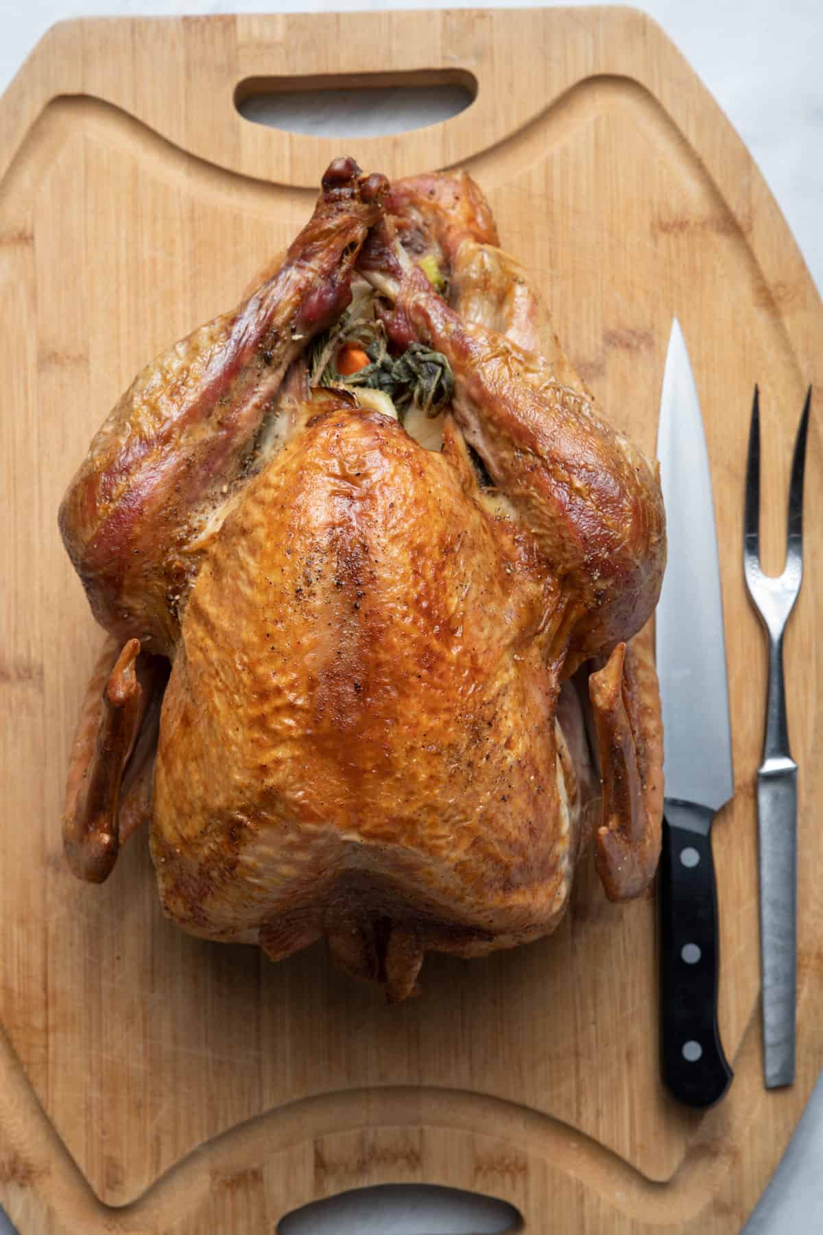 Thanksgiving turkey on a large cutting board with carving tools