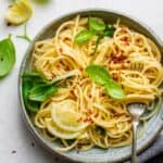 Final plated dish of the hummus pasta topped with lemon slices, basil and crushed garlic