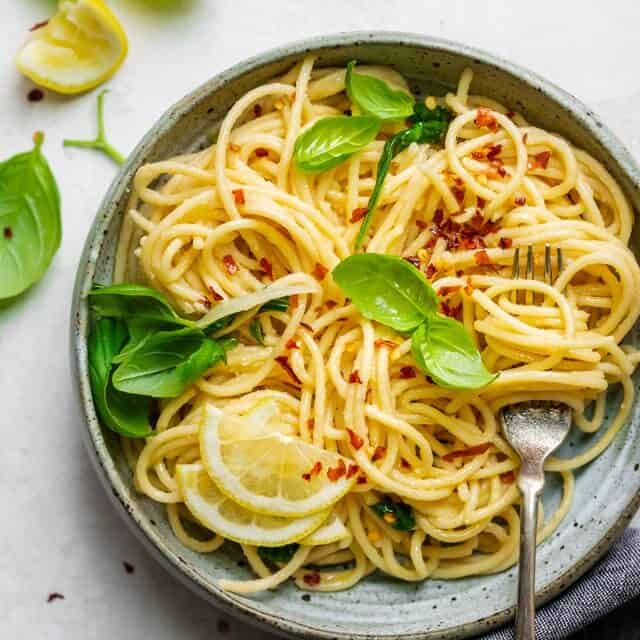 Final plated dish of the hummus pasta topped with lemon slices, basil and crushed garlic
