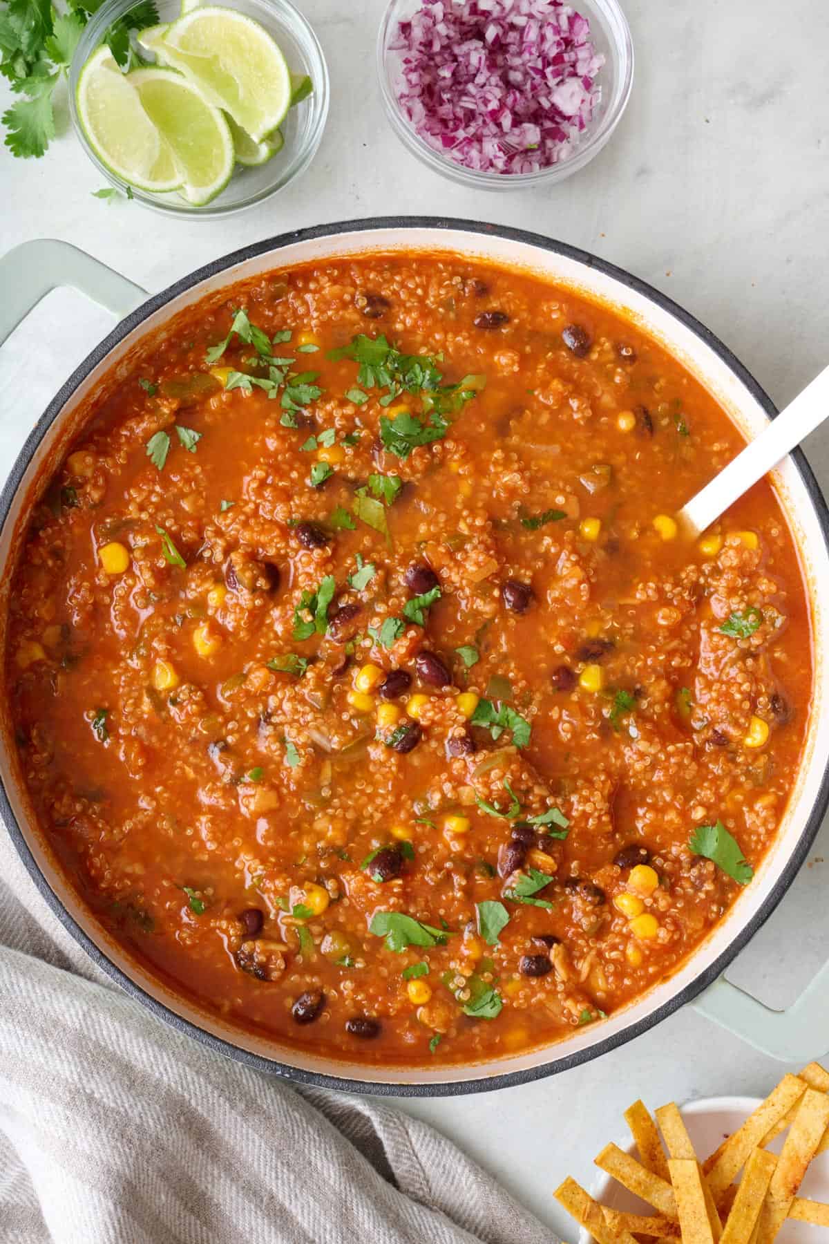 Vegetarian tortilla soup in a pot with ladle dipped in.