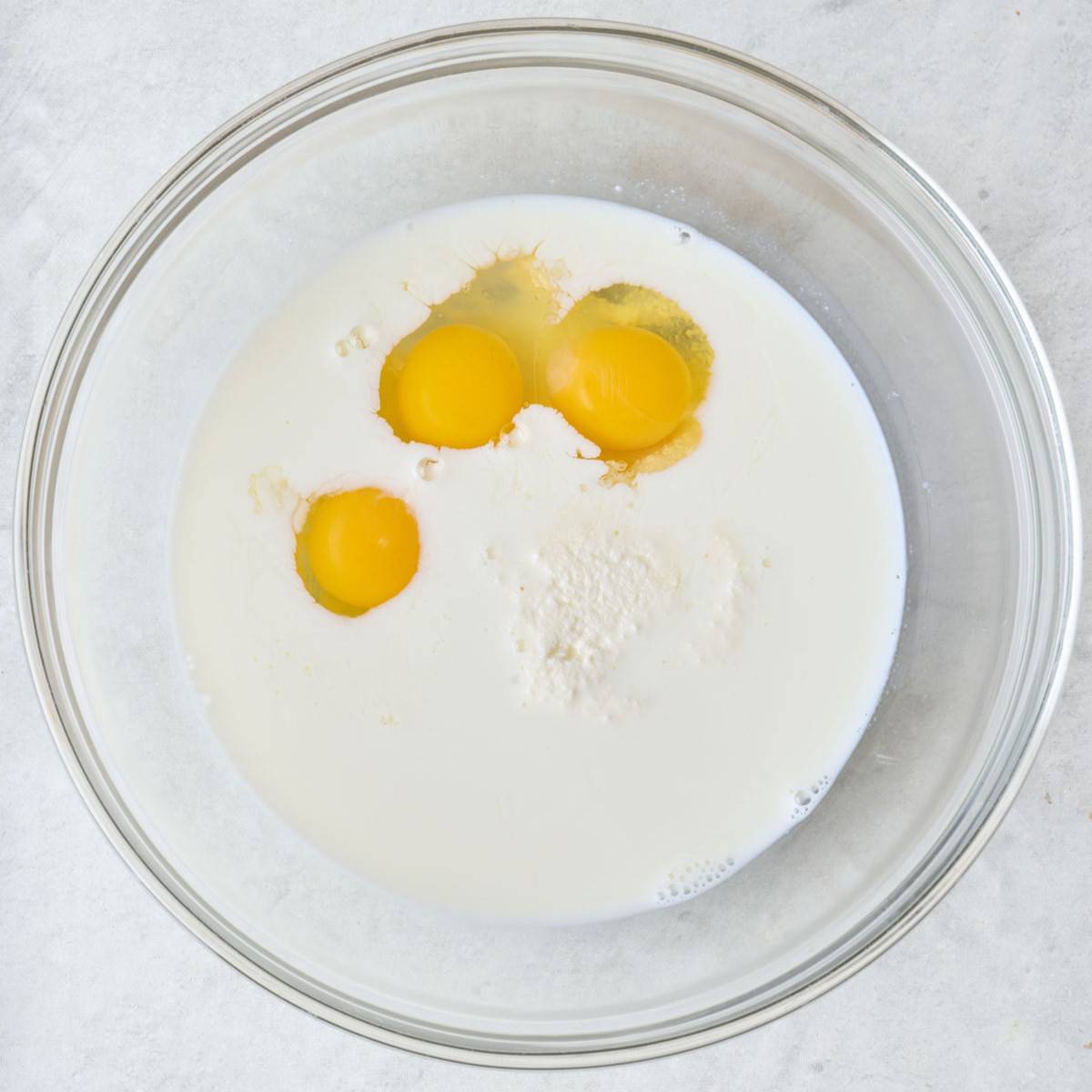 Milk, eggs, ricotta, and lemon in a bowl.
