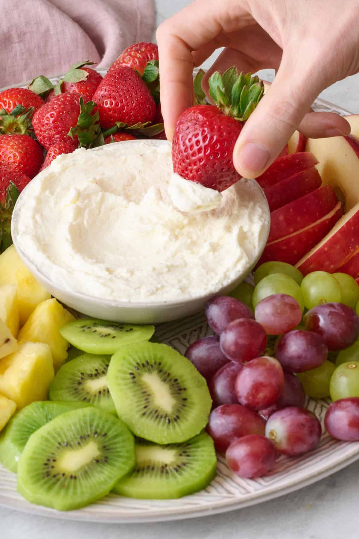 Dipping a strawberry into cream cheese dip.
