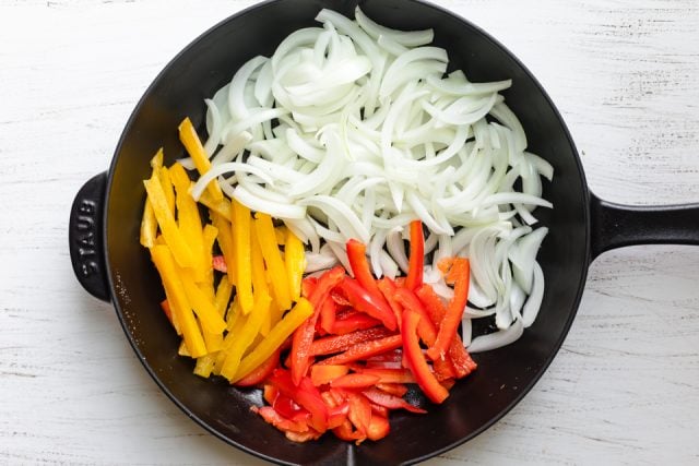 Cast iron skillet with onions yellow peppers and red peppers