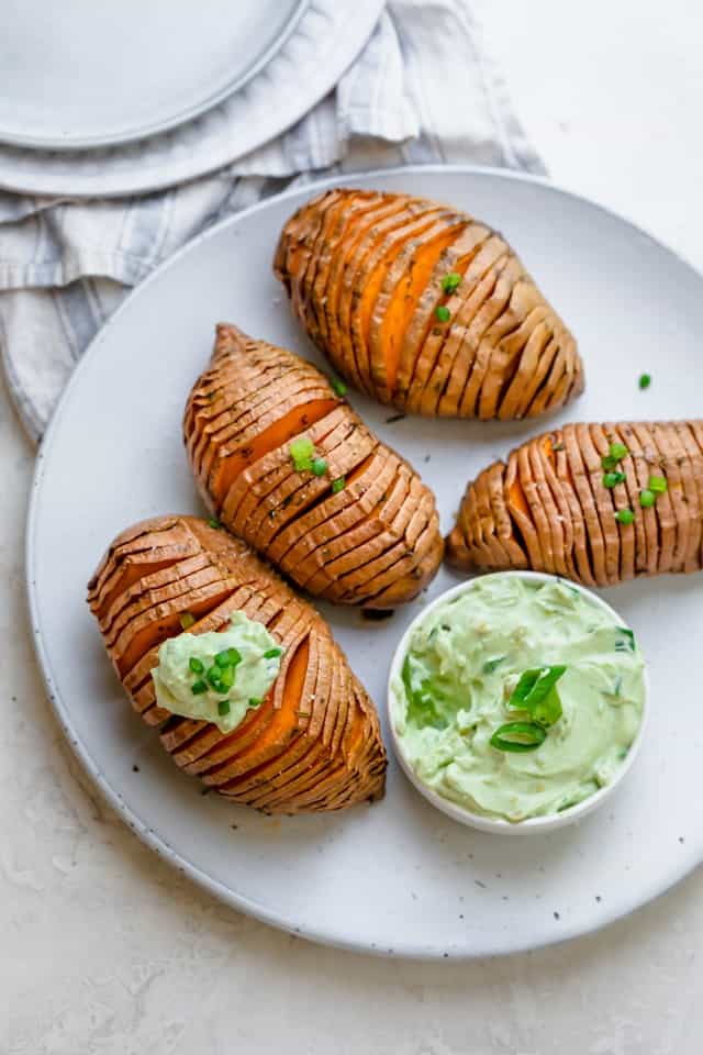 Sweet potatoes on a serving platter with yogurt dip next to it.