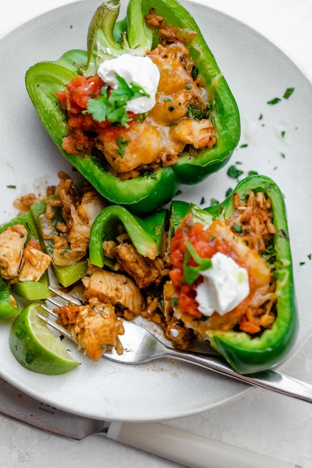 Fork cutting piece out of chicken stuffed peppers to show inside stuffing