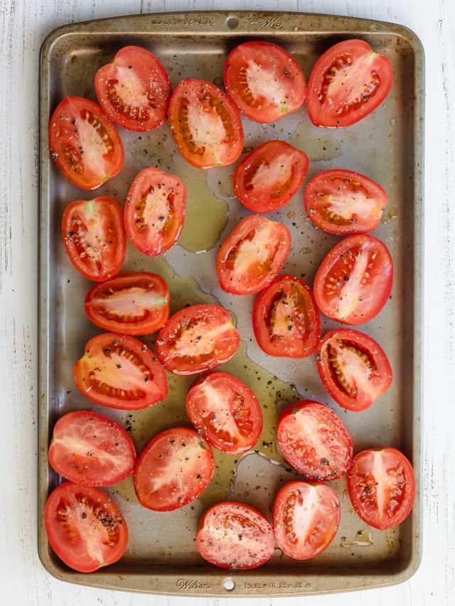 Tomatoes on a baking sheet before roasting.