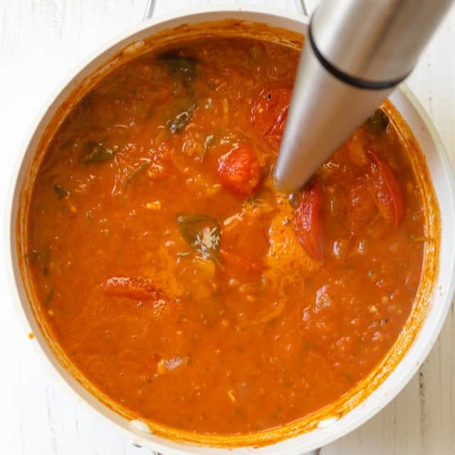 Blending the soup with an immersion blender.