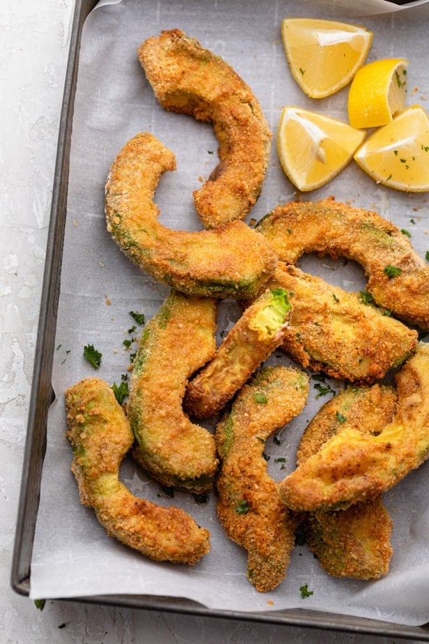 Avocado fries served on a try with lemon wedges