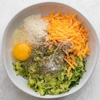 Ingredients for the zucchini tots in a bowl before combining.