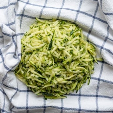 Zucchini shreds in a kitchen towel.