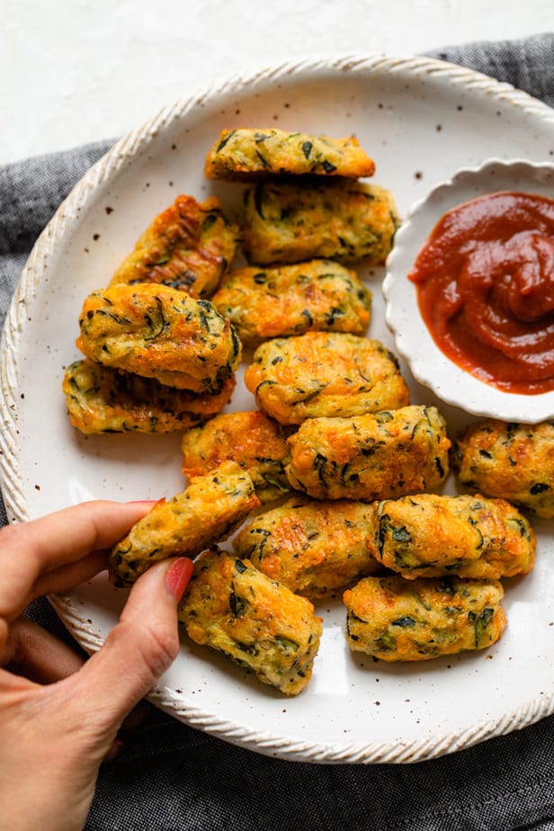 Picking up a zucchini tot to dip in the ketchup