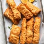 Breaded fish after air fried on a tray with lemon wedges