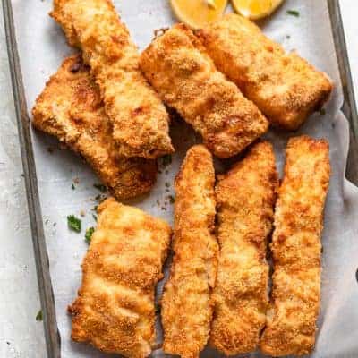 Breaded fish after air fried on a tray with lemon wedges