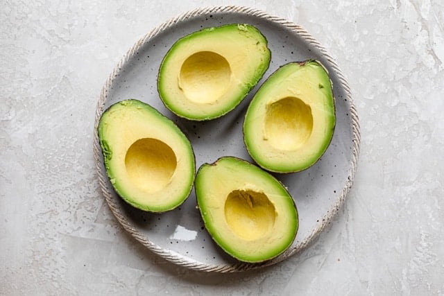 Two avocados halved and pitted