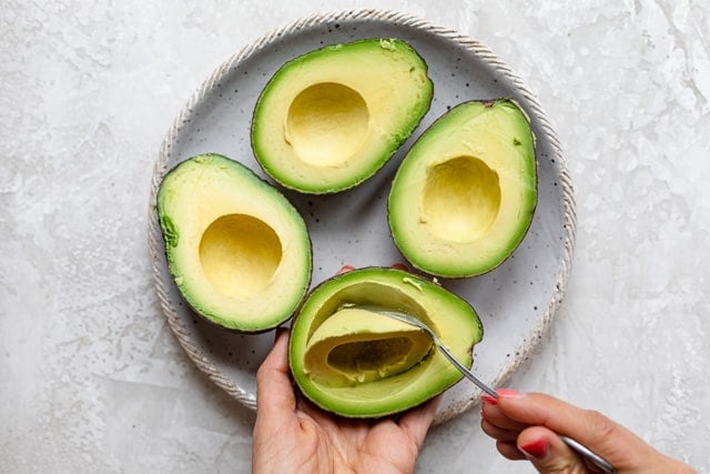 Removing some flesh from avocados with spoon