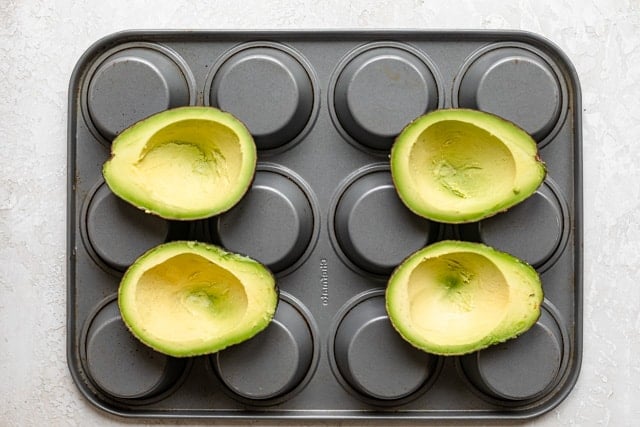 Placing avocados inside muffin tins for baking