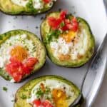 Taking a spoonful of the baked eggs in avocado