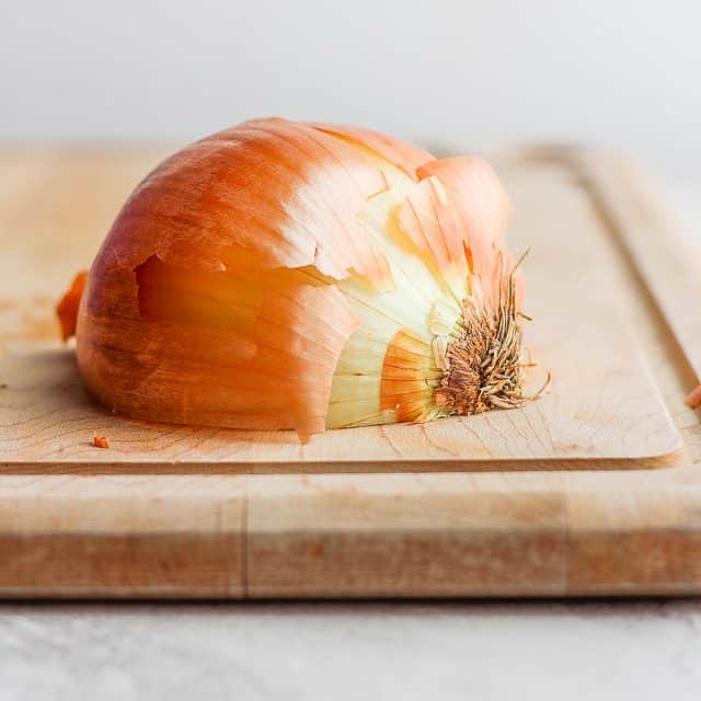 Laying half the onion on cutting boards cut size down