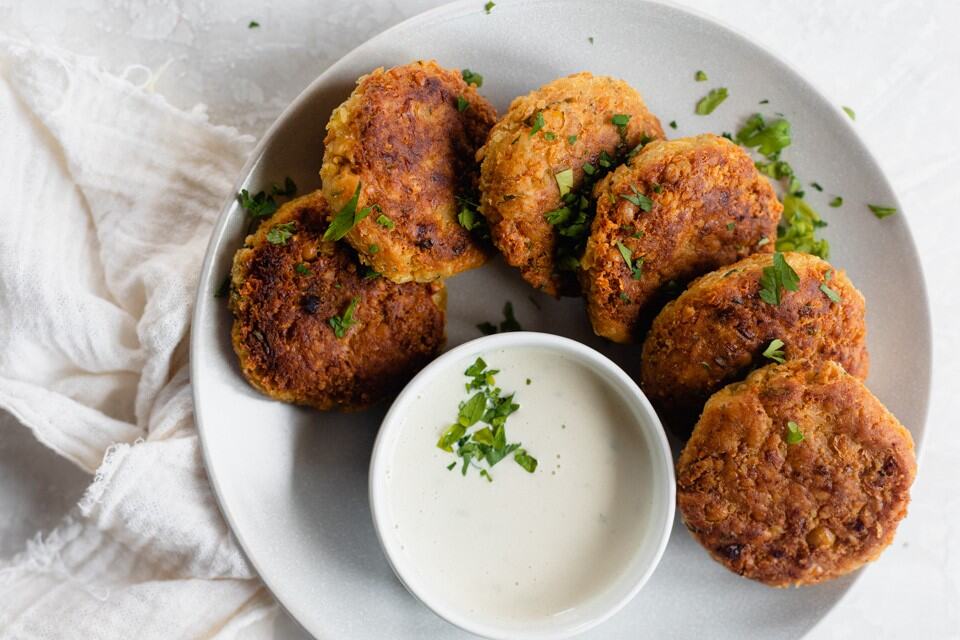 Chickpea fritters on a plate with a bowl of dipping sauce.