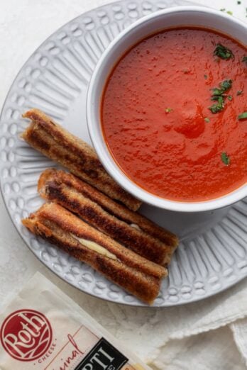 Grilled cheese dippers on a plate next to bowl of tomato soup