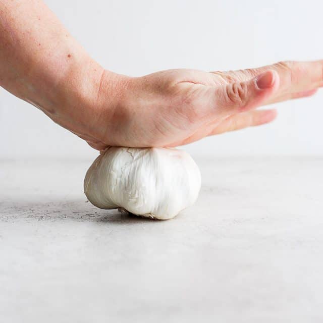 hand crushing a bulb of garlic
