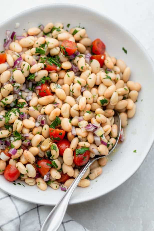 Close up of a spoon in the white bean salad