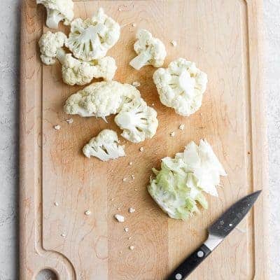 Cut cauliflower florets on a cutting board with a knife - tutorial for how to cut cauliflower