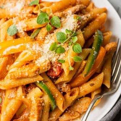 Chicken fajita pasta on a white plate with a fork on the plate